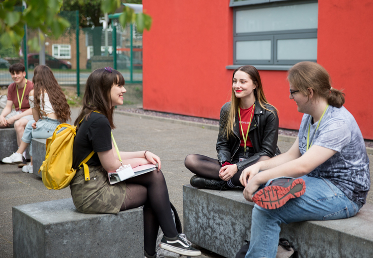 3 students sat on outside sitting area