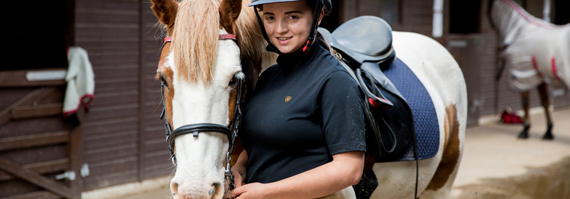 Young lady in riding gear with horse