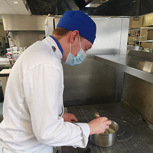Learner Morgan Upcott in chef's whites cooking