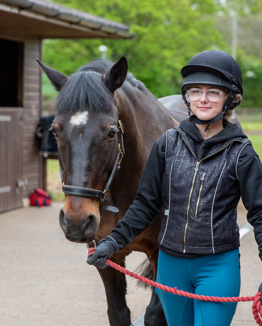Equestrian student leading horse by reins