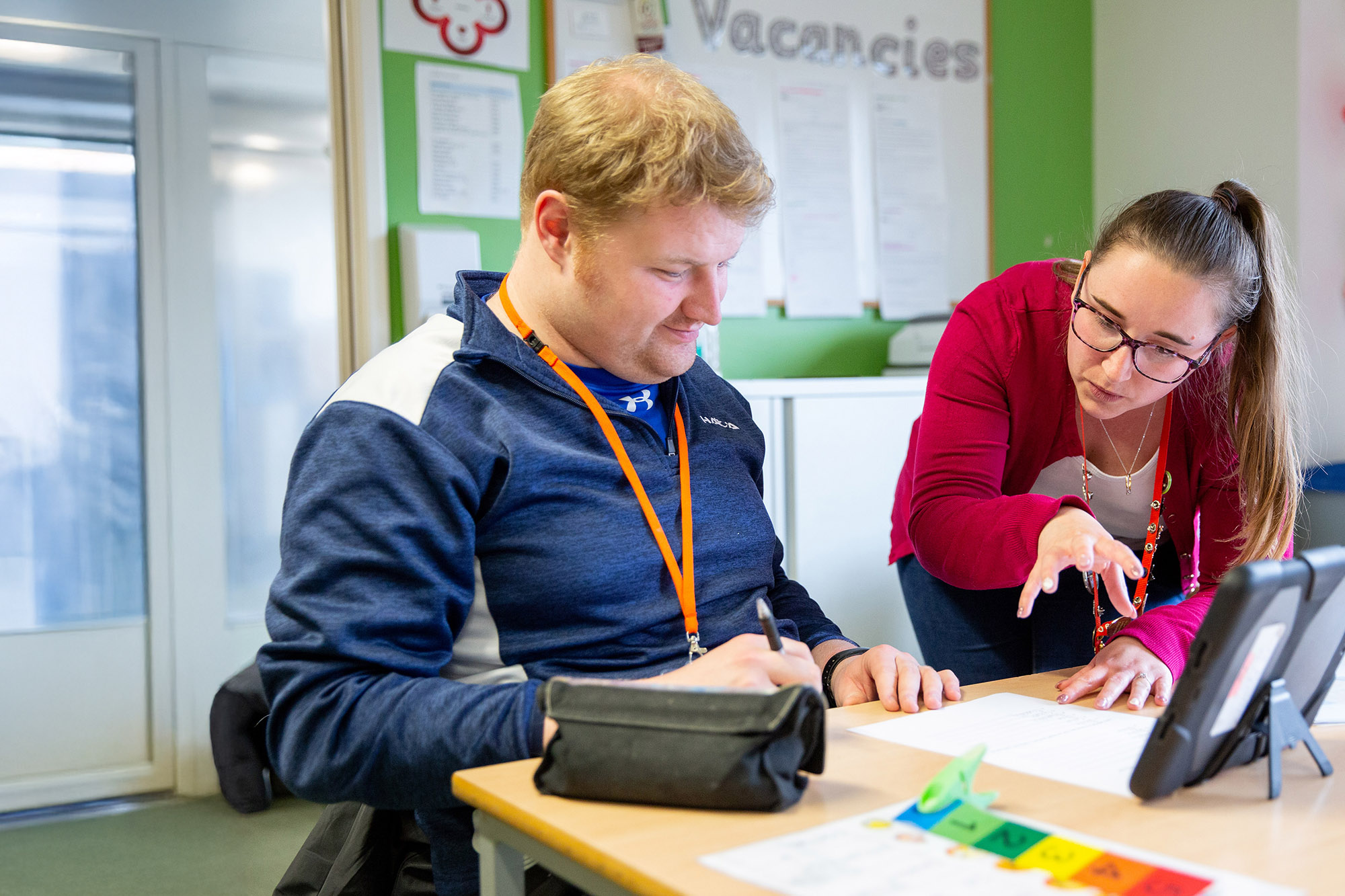 CG member of staff helping a learner with their work.