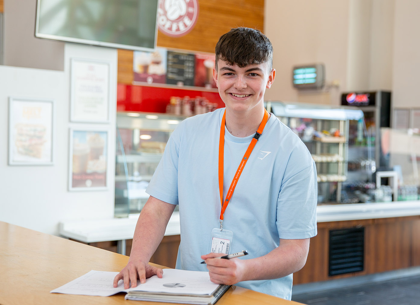Student smiling whilst studying in cafe area