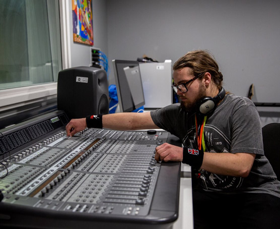 Student operating a mixing desk in the sound recording studio