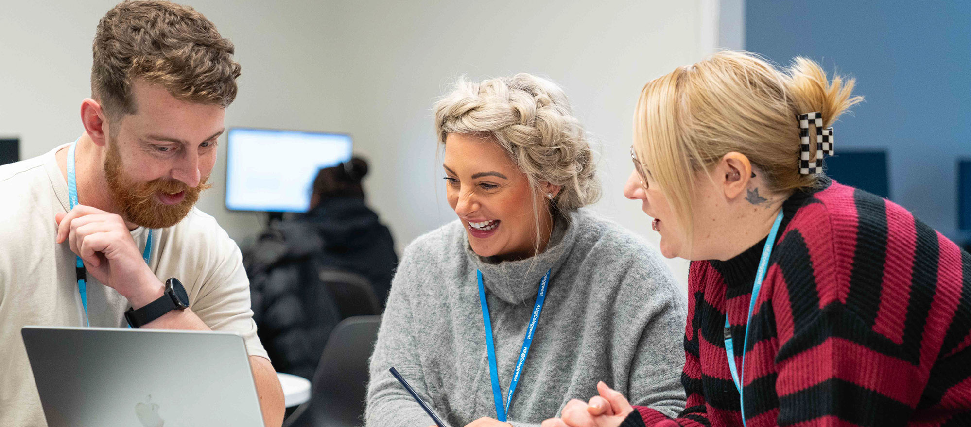 Three students sat around a laptop