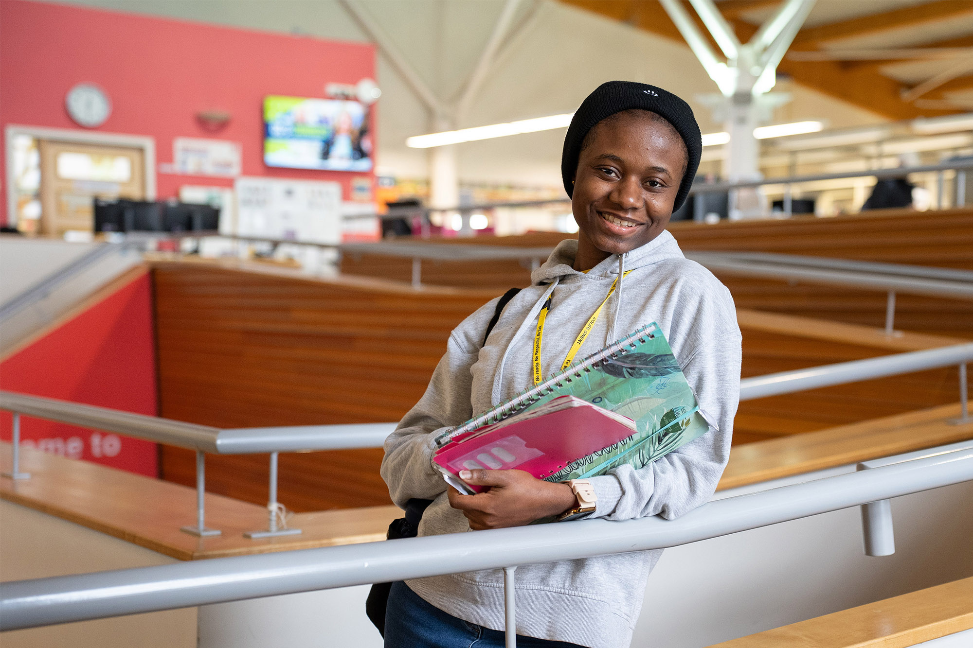 Smiling student stood on stairway holding books
