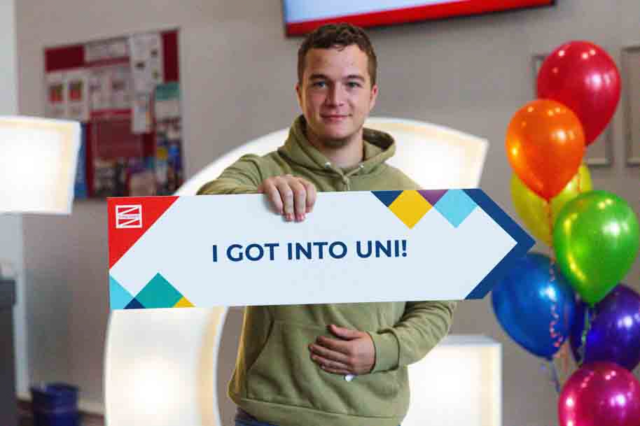 Student holding up a "I got into uni" sign