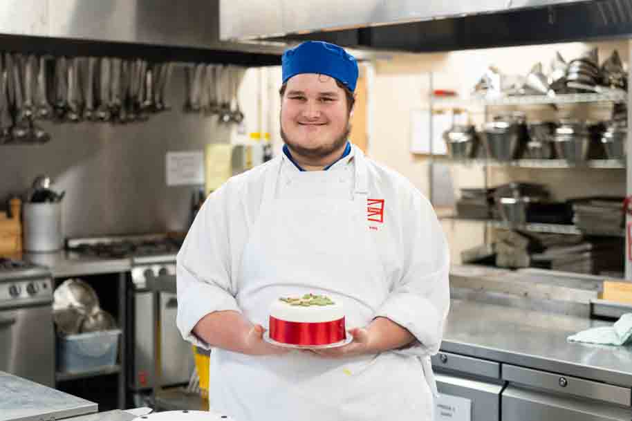 Catering student holding freshly baked Christmas cake