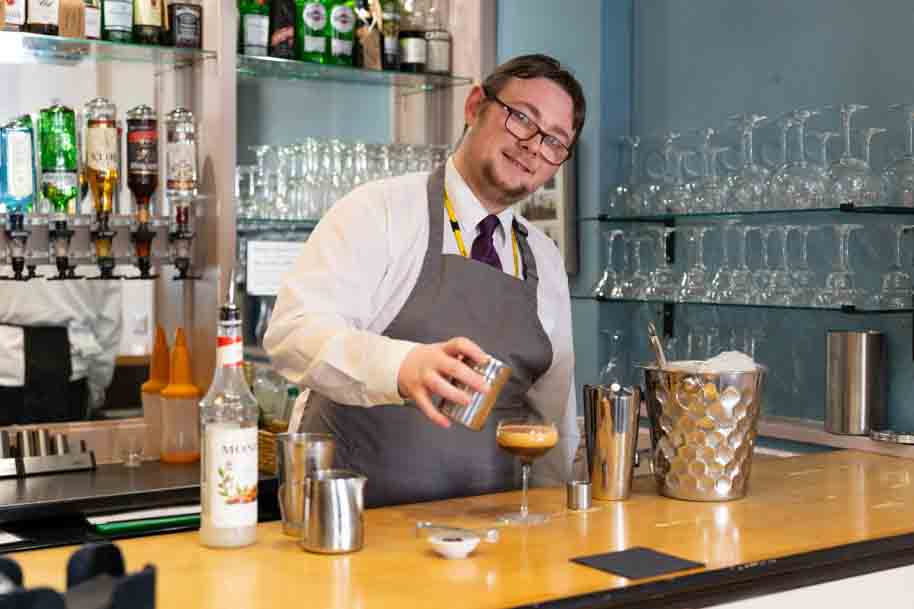 Hospitality student smiling behind bar at Morels restaurant