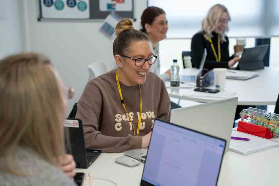 Student working on laptop and chatting with friends