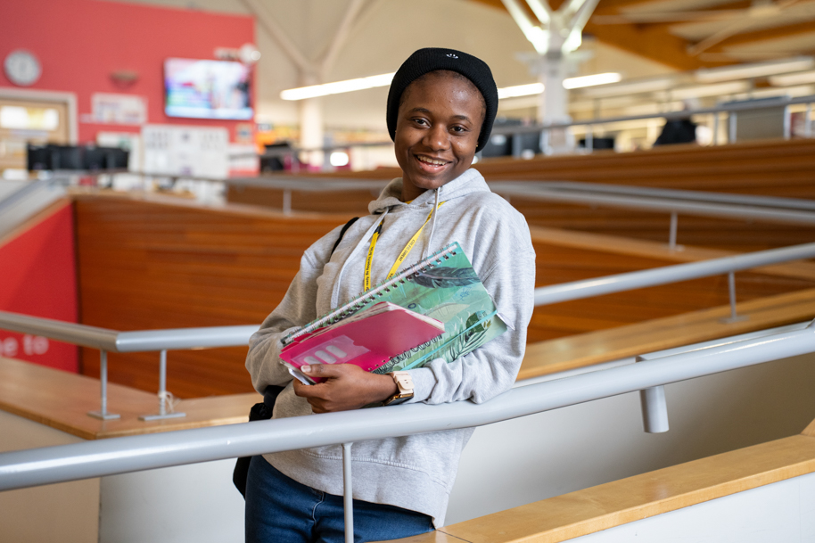 Student smiling and holding books in library