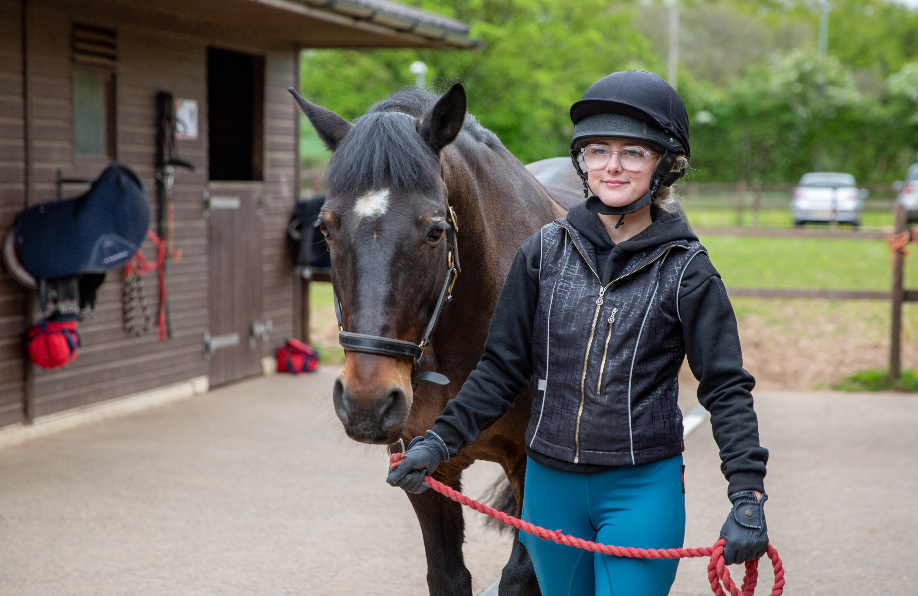 Student walking a horse through the stables