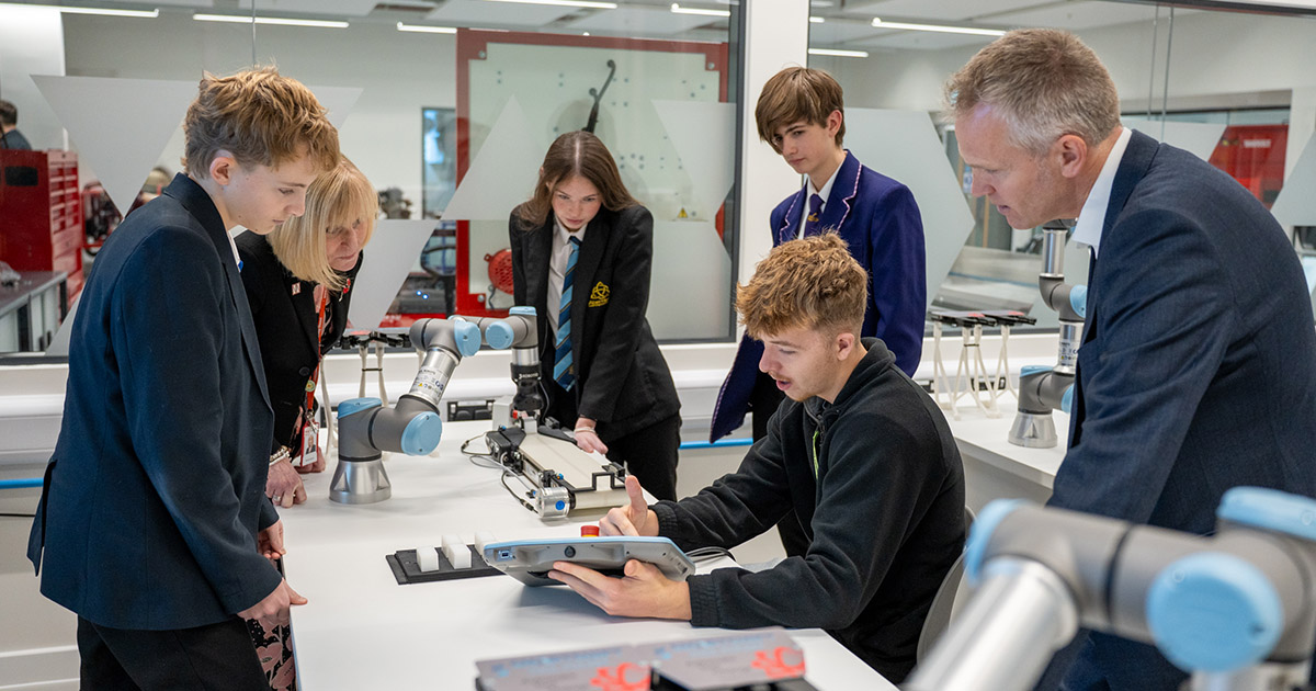 Students demonstrating robotic arms using a tablet