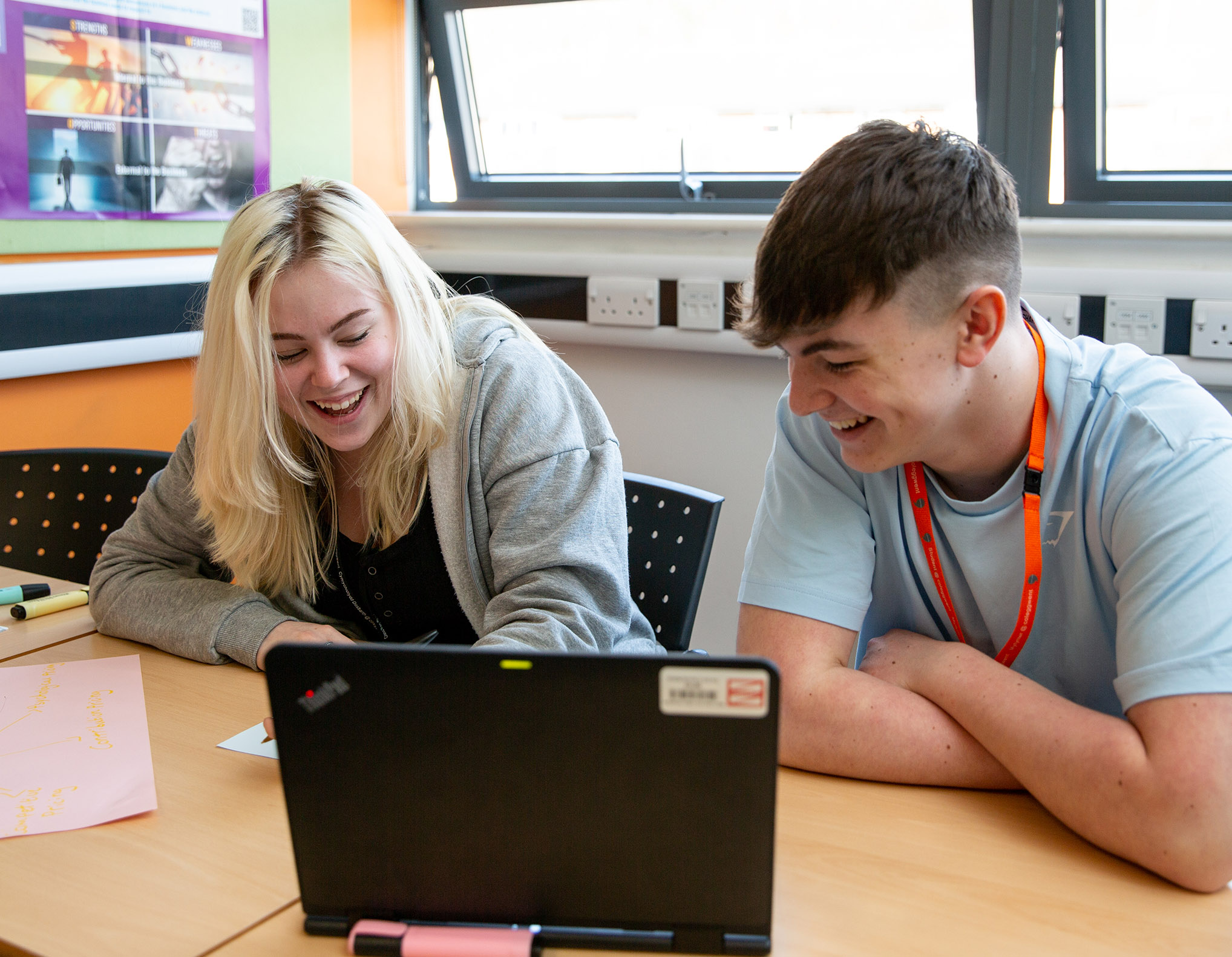 Students sat in front of laptop laughing